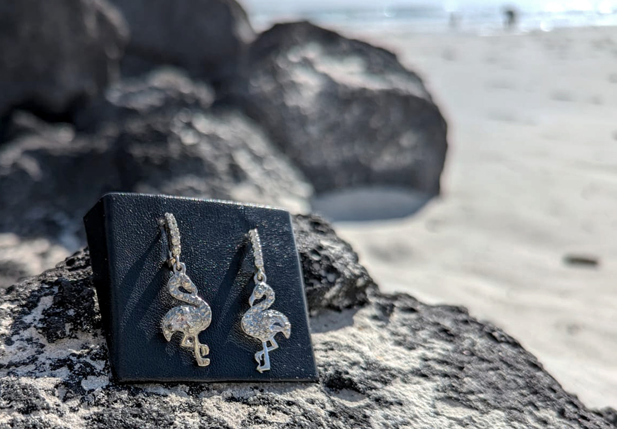 Drop flamingo earrings on lava rock at beach