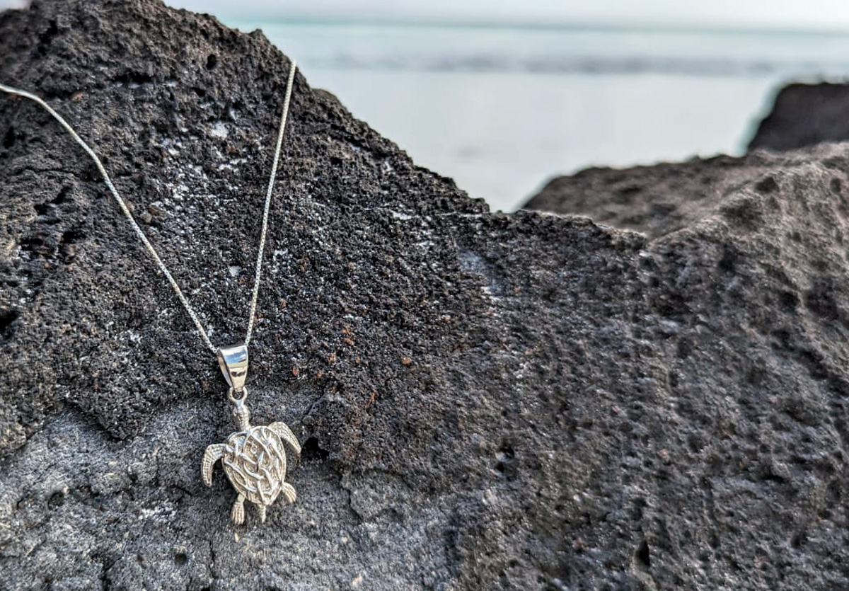 Sea turtle pendant on lava rock at beach