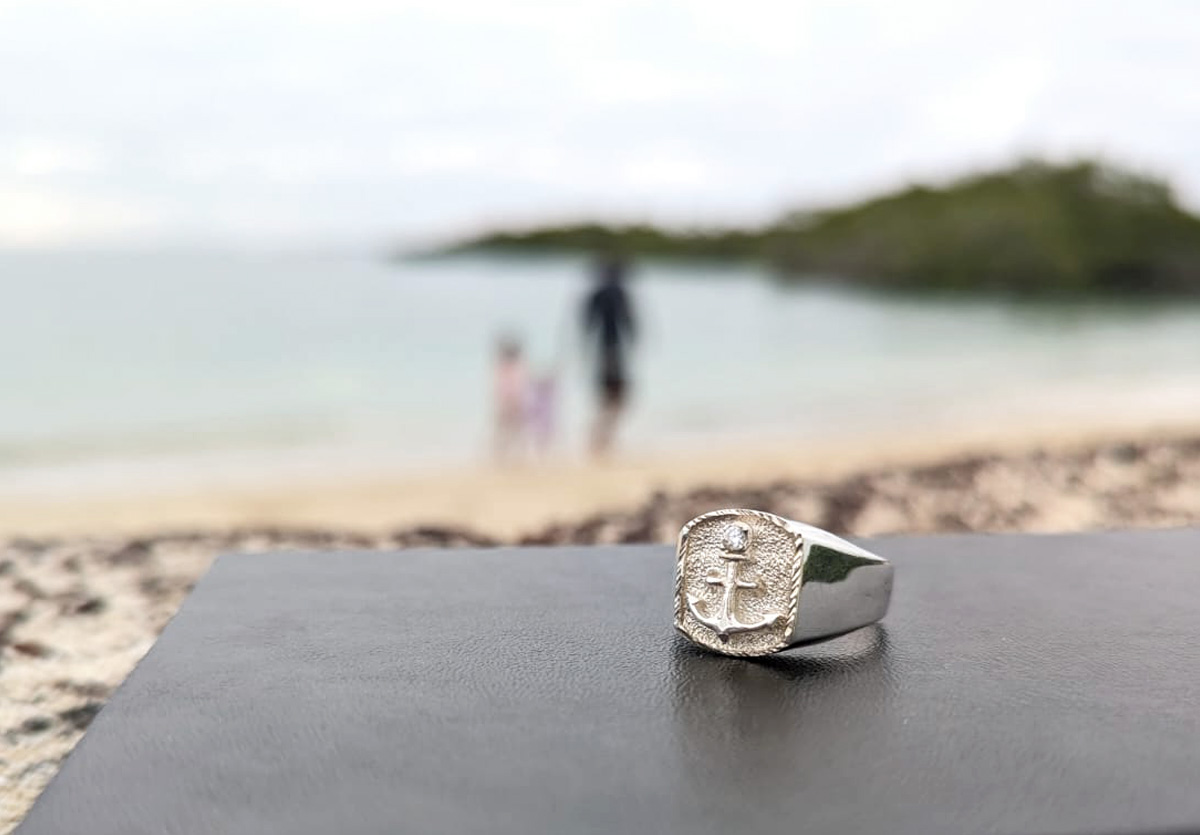 Silver ring with anchor on beach